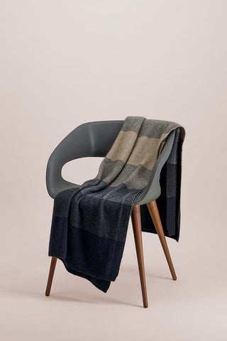 A dapple multicolored ombre pattern throw draped over a chair.