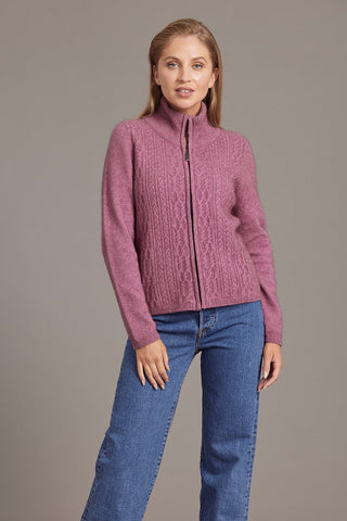 A woman wearing a heather pink zip-up jacket with lace cable detailing, paired with blue jeans.