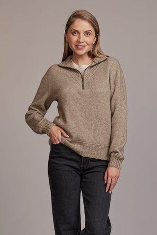 A woman wearing a beige McDonald sweater with a funnel neck and a 1/4 zip, paired with black pants.