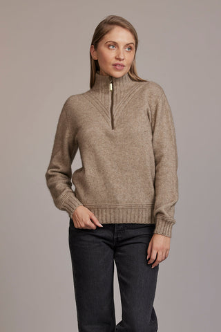 A woman wearing a beige McDonald sweater with a funnel neck and a 1/4 zip, paired with black pants.
