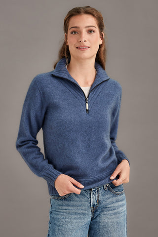 Woman wearing a blue pullover with a zipper on a gray background