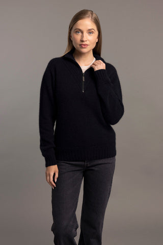 A woman wearing a navy McDonald sweater with a funnel neck and a 1/4 zip, paired with black pants.