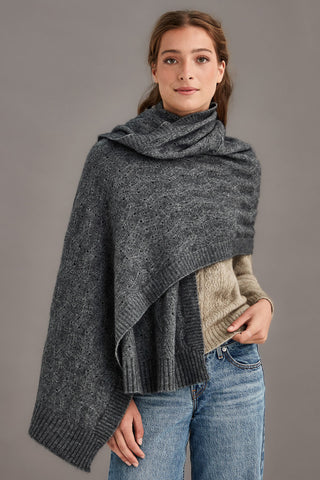 Woman wearing a pewter gray knitted shawl over a brown sweater against a gray background
