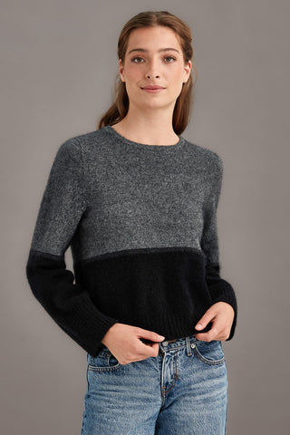 Woman wearing a colourblocked sweater with black and gray against a plain background
