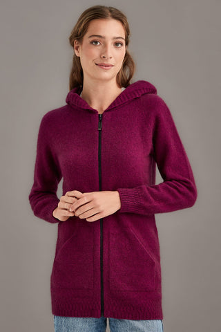 Woman wearing a berry pink hooded knit jacket against a gray background
