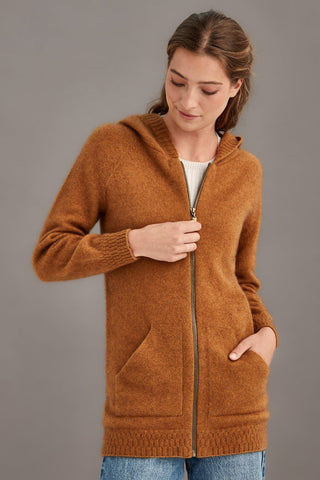 Woman wearing a honey brown hooded knit jacket against a gray background