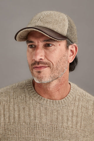 Man wearing a bark and mocha cap and sweater against a gray background