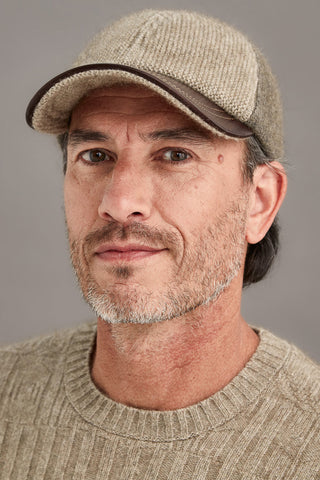 Man wearing a bark and mocha cap and sweater against a gray background