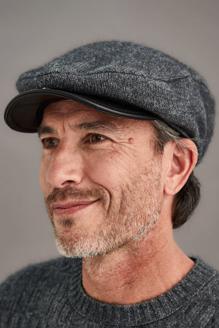 Man wearing a gray cap and sweater against a neutral background