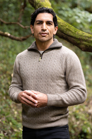 A man wearing a beige cable knit jersey with contrast trim standing outdoors.