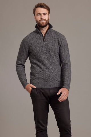 A man wearing a pewter grey cable knit jersey with contrast trim standing outdoors.