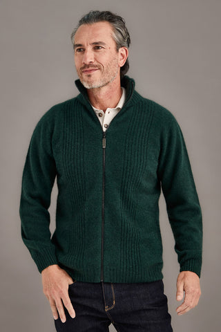 Man wearing a green zip-up sweater against a gray background