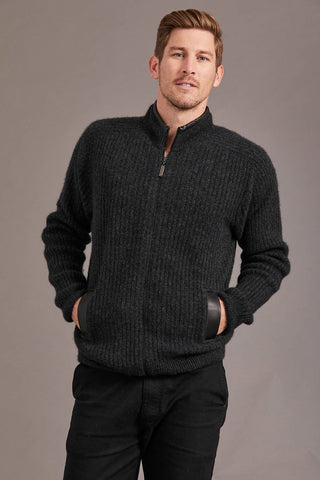 Man wearing a charcoal grey knitted jacket against a plain background