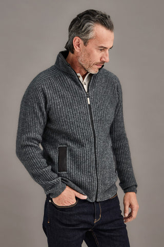Man wearing a gray knitted jacket against a plain background