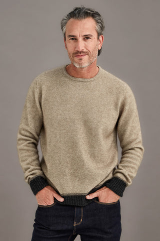 Man wearing a ash brown sweater with contrasting colour bands against a plain background