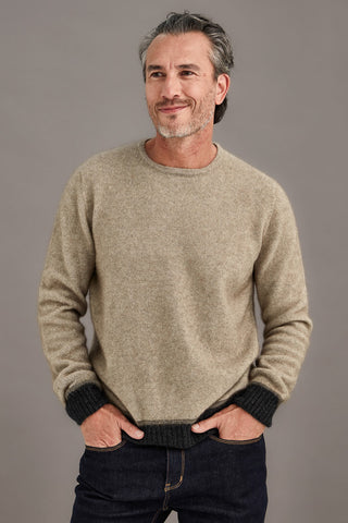 Man wearing a ash brown sweater with contrasting colour bands against a plain background