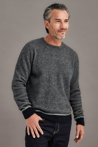 Man wearing a gray sweater with contrasting colour bands against a plain background