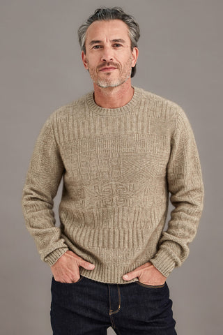 Man wearing a mocha brown detailed sweater against a plain background