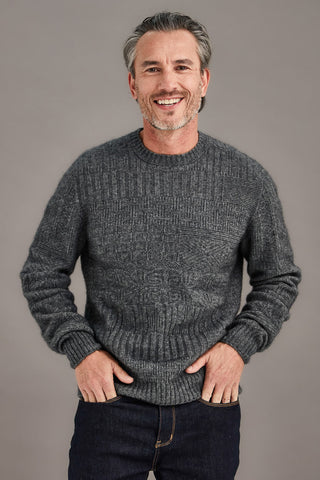 Man wearing a pewter gray detailed sweater against a plain background
