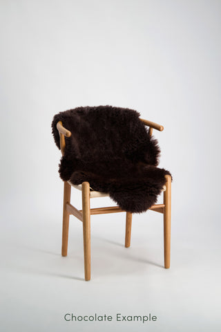 Ecowool Natural Undyed Sheepskin Rugs – Single. Chair with a dark brown fur cover on a white background