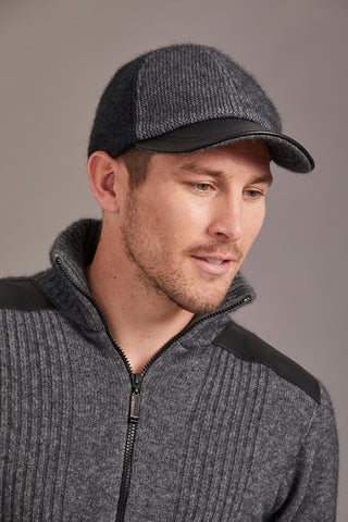 Man wearing a charcoal and pewter cap and sweater against a gray background