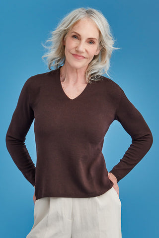 Woman wearing a brown merino sweater against a blue background