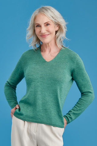 Woman wearing a green merino sweater against a blue background
