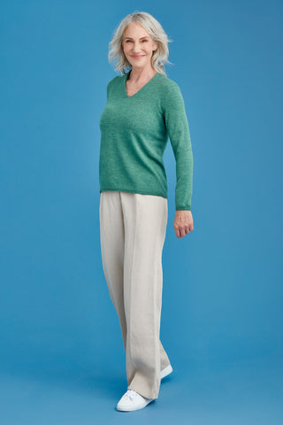 Woman wearing a green merino sweater against a blue background
