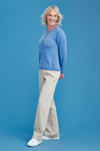 Woman wearing a blue sweater and beige pants against a blue background