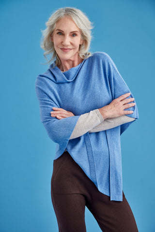 Woman wearing a blue poncho over a grey shirt against a blue background