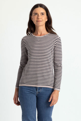 Woman wearing a light sand and navy striped sweater against a white background