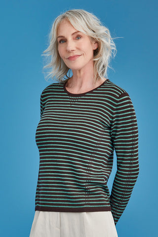 Woman wearing a green and brown striped sweater against a blue background