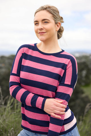 A woman standing outdoors wearing a pink and white striped drop shoulder jumper