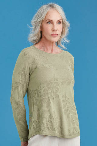 Woman wearing a light green patterned sweater against a blue background