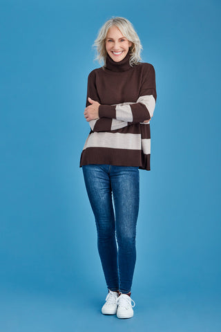 Woman wearing a brown and white striped merino sweater against a blue background