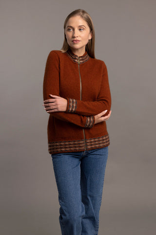 A woman is wearing a spice zip-up cardigan with wave pattern trim, paired with black pants.