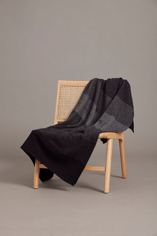 A monochrome multicolored ombre pattern throw draped over a chair.
