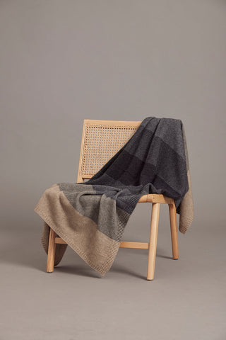 A sepia multicolored ombre pattern throw draped over a chair.
