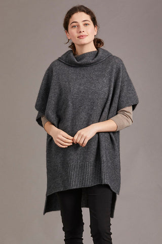 A model wearing a gray poncho with a cowl neck and a step level hem, standing against a neutral background.