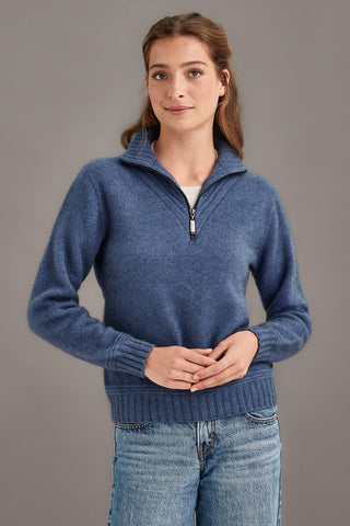 Woman wearing a blue sweater with a zipper on a gray background