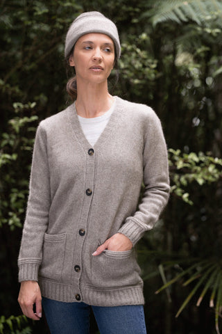 Woman wearing a mocha and bark knitted hat and cardigan sweater outdoors