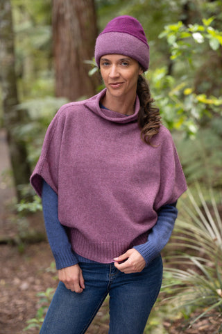Woman wearing a heather and berry knitted hat and shrug sweater outdoors