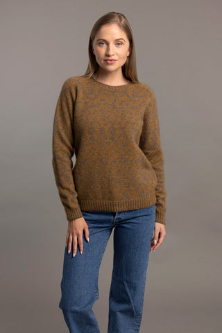 A woman wearing a brown toned Fair Isle pullover sweater with intricate patterns, paired with black pants.