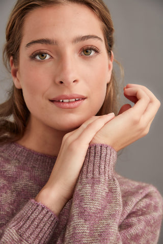Woman wearing a heather and mocha patterned sweater against a gray background