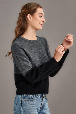 Woman wearing a colourblocked sweater with black and gray against a plain background