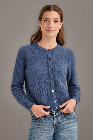 Woman wearing a blue knitted cardigan against a gray background