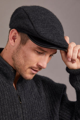 Man wearing a gray cap and sweater against a gray background