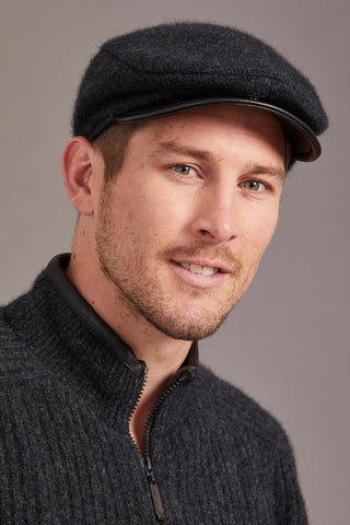 Man wearing a gray cap and sweater against a gray background