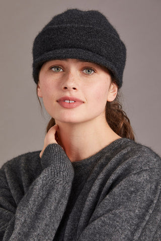 Woman wearing a charcoal knit cap and sweater against a neutral background