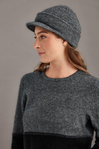 Woman wearing a gray knit cap and sweater against a neutral background